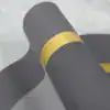 Dywanik łazienkowy w kolorze szarym ze złotą wstążką, zwinięty w rolkę.