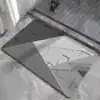 Dywanik łazienkowy w stylu geometrycznym, wzór z trójkątami i liniami, kolor szary i biały.