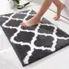 Dywanik łazienkowy w kolorze szarym z białym wzorem geometrycznym, na białej podłodze.