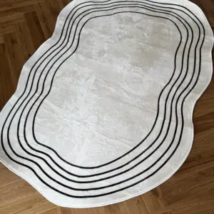 Biały dywanik z czarnymi falistymi liniami na drewnianej podłodze.