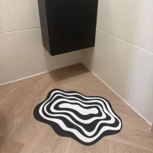Mały dywanik w czarno-białe fale w narożniku łazienki.