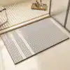 Dywanik łazienkowy w stylu minimalistycznym z geometrycznym wzorem w kolorach szarych i białych.
