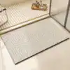 Dywanik łazienkowy z geometrycznym wzorem w odcieniach szarości, na podłodze w łazience.
