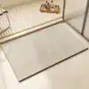 Dywanik łazienkowy w kolorze beżowym z geometrycznym wzorem w paski.